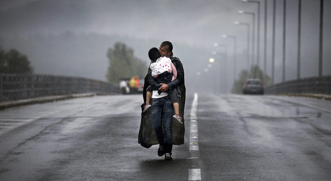 A Syrian refugee kisses his daughter as he walks through a rainstorm towards Greece's border with FYRO-Macedonia, near the Greek village of Idomeni, September 10, 2015. Thousands of refugees and migrants, including many families with young children, have been left soaked after spending the night sleeping in the open in torrential rain on the Greek- FYRO Macedonian border. REUTERS/Yannis Behrakis